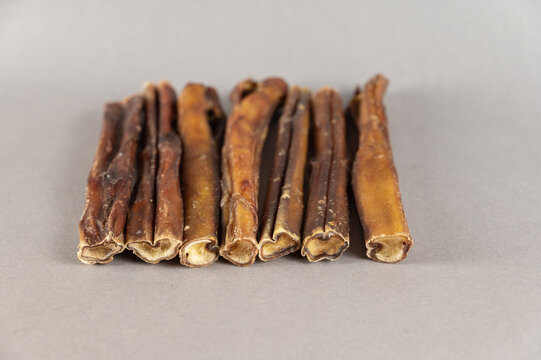 Pet chew treats. Natural dried dog treats against a gray background. Group of bully sticks. Pet supplies.