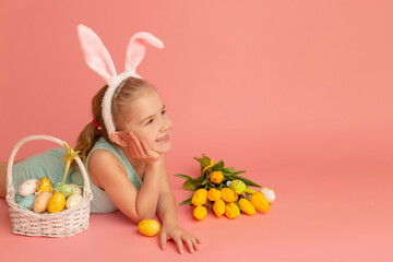 Closeup portrait of a smiling little girl on a pink background with an easter decor. Copy space. Happy easter
