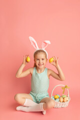 Obraz na płótnie Canvas Portrait of cute smiling girl with Bunny ears and Easter basket, isolated on pink background. Happy Easter. Vertical photo