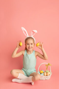 Portrait of cute smiling girl with Bunny ears and Easter basket, isolated on pink background. Happy Easter. Vertical photo