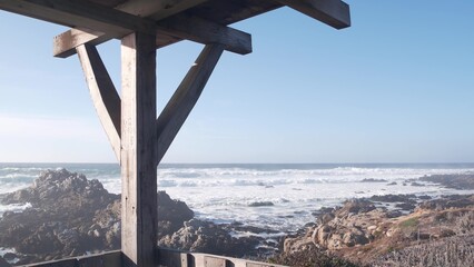 Big stormy waves crashing, rocky craggy beach, Monterey shore, California ocean coast USA. 17-mile drive nature. Sea water splashing, landscape or seascape. Pebble beach. Wooden gazebo alcove on trail