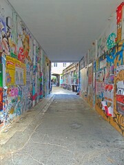 Posters and graffiti  covering an alleyway 