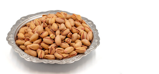 Shelled pistachios isolated on a white background. Pistachios on a rustic serving plate. Copy space. Space for text area