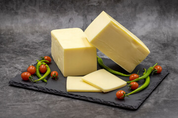 Cheddar cheese or kashkaval cheese on dark background. Cheese slices on the serving board
