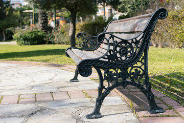 forged wooden bench in the city square in the park, green grass around