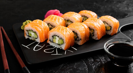 Traditional sushi - Philadelphia with salmon, cucumber avocado and cream cheese. Japanese cuisine. Top view. Black background.	