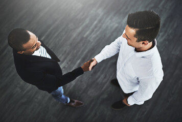 Two greats merging to make business greater. High angle shot of two businessmen shaking hands in an...