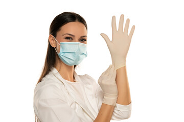 Beautiful female doctor or nurse wearing protective mask and latex or rubber gloves on white background with copyspace.