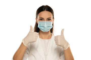 Beautiful female doctor or nurse wearing protective mask and latex or rubber gloves on white...
