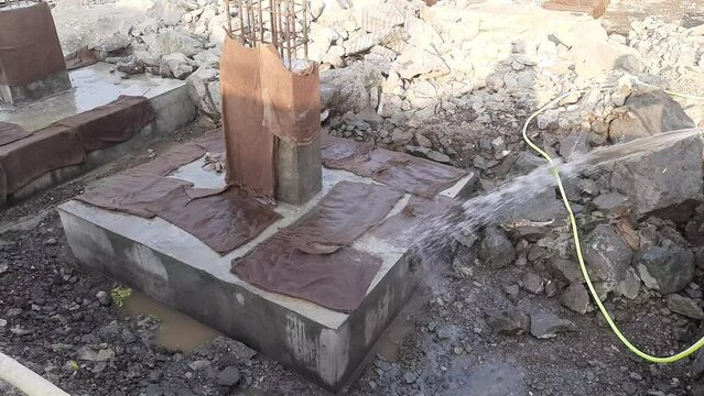 Workers giving water at the foot of the site under construction for strength - Builder Worker Sprays Water on the footing