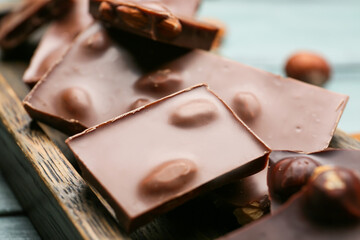 Pieces of tasty chocolate with nuts on board, closeup