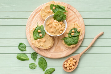 Board with pieces of bread and tasty hummus on table