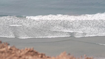 Steep cliff or bluff, California coast, USA. Torrey Pines, ocean tide by beach, big waves crashing, sea foam. Seascape top down aerial view from above. Water surface. Seamless looped cinemagraph.