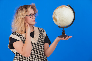 Learning about the globe. Geography concept. Young teenage girl in glasses holding artificial globe...