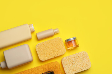 Different cosmetic products, sponges and towel on yellow background, closeup
