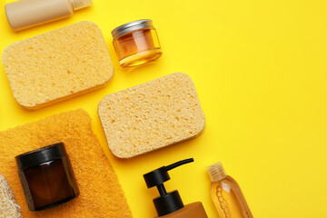Different cosmetic products, sponges and towel on yellow background, closeup