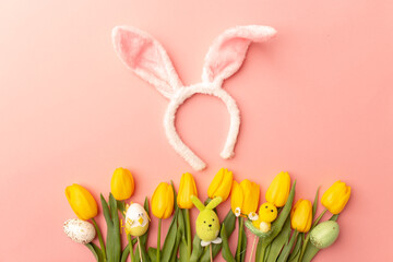 Yellow tulips and Bunny ears on a pink background, top view. Happy easter. Spring bouquet