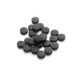 Heap of activated carbon pills on white background