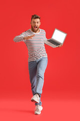 Cool dancing young man with laptop on color background