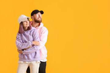 Cool young couple in hoodies on color background