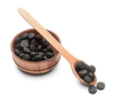 Bowl and spoon with activated carbon pills on white background