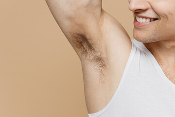 Cropped close up young man 20s perfect skin in undershirt look at unshaven armpit with deodorant...