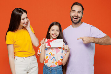 Young happy parents mom dad with child kid daughter teen girl in basic t-shirts hold gift...