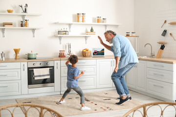 Little boy with his grandfather dancing in kitchen