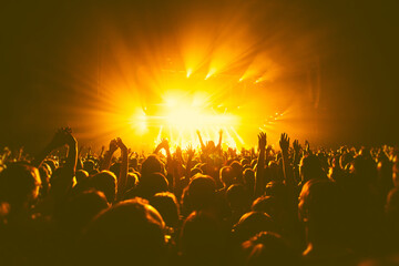 A crowded concert hall with scene stage orange and yellow lights, rock show performance, with...