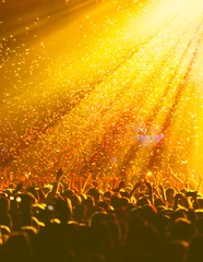 Foto auf Alu-Dibond A crowded concert hall with scene stage orange and yellow lights, rock show performance, with people silhouette, colourful confetti explosion fired on dance floor air during a concert festival © tsuguliev