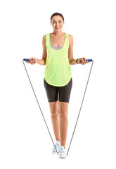 Sporty young woman with skipping rope on white background