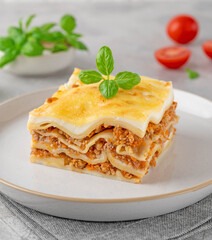 Slice of Lasagna bolognese with meat sauce and bechamel with melted cheese on top and fresh basil. Italian cusine. Copy space.