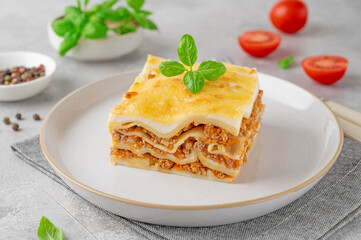 Slice of Lasagna bolognese with meat sauce and bechamel with melted cheese on top and fresh basil. Italian cusine. Copy space.