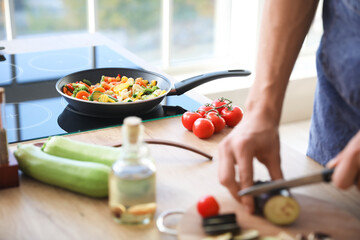 Frying pan with healthy vegetables on stove in kitchen, closeup