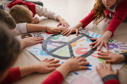 Schoolchildren making poster of peace sign at school.