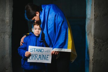 Naklejka na ściany i meble Sad mother hugging her son, both wearing Ukrainian national colors on black background.