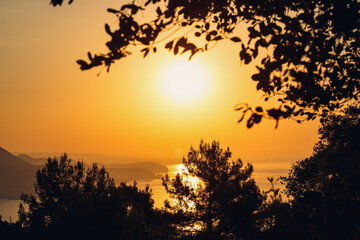 Obraz premium The sun sets on the horizon at sunset over the sea or ocean. Calm ocean sea waves. Natural sky in warm colors. Panoramic view,