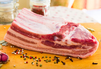 fresh piece of pork belly on wooden board with spices