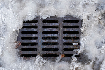 sewer grate covered with melting snow. Selective Focus