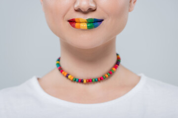 cropped view of woman with lgbt colors necklace and lips isolated on grey.
