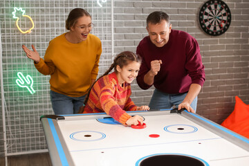 Family playing air hockey indoors