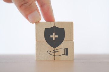 security with hospital or clinic symbol inside over hand icon on wooden cube blocks for health...