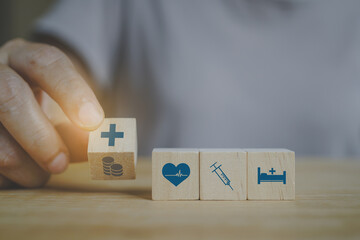 senior's hand flipped wooden cube  block, coin to hospital symbol, and   health and medical symbol for health insurance ,wellness , wellbeing concept
