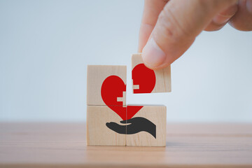 hand completed red heart shaped over hand icon on wooden block cubes, square shape, for health...