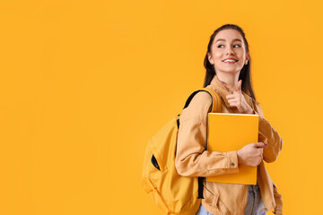 Portrait of beautiful female student showing something on color background