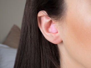 pink ear plug in the ear close-up. peace and quiet throughout the night.