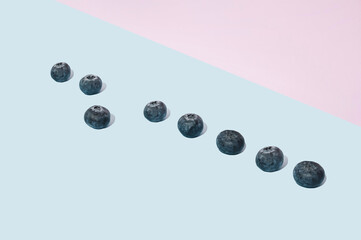 Minimal healthy lifestyle concept with blueberries on pink and blue background. Modern aesthetic.