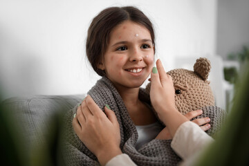 Mother applying remedy on skin of her little daughter ill with chickenpox at home