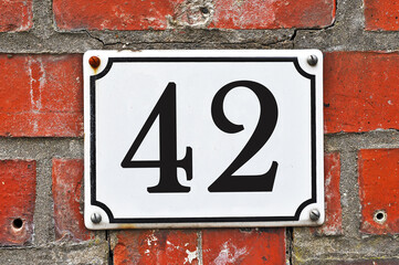 Sign of a street number 42 on a red brick wall - obrazy, fototapety, plakaty