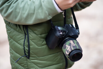 Close-up of modern photo camera. Person in coat with digital camera with big lens. Technology, hobby concept